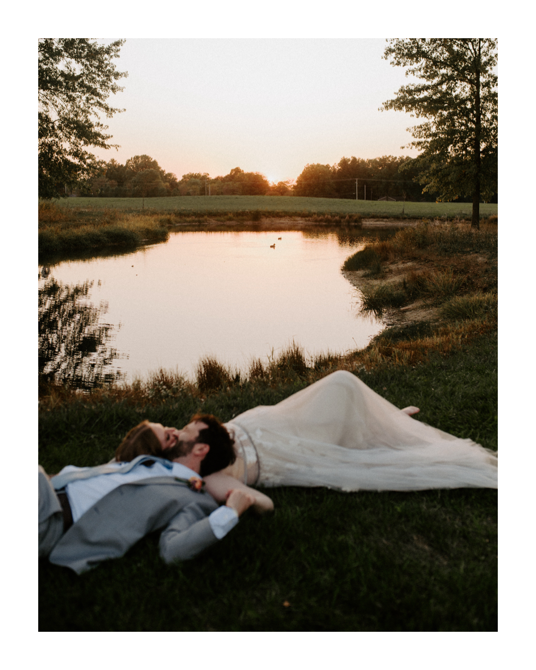 Romantic moment between bride and groom laying by the pond at Jorgensen Farms in Westerville, Ohio, captured by Ashley Wallace Photography. Intimate, serene wedding portrait in a picturesque outdoor setting.